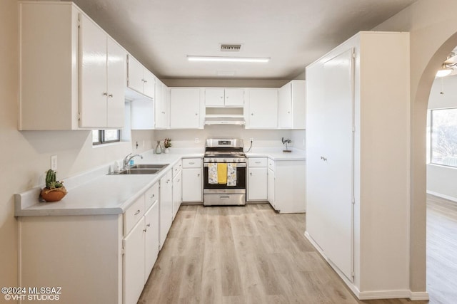 kitchen with white cabinetry, stainless steel range with gas stovetop, sink, and light hardwood / wood-style flooring