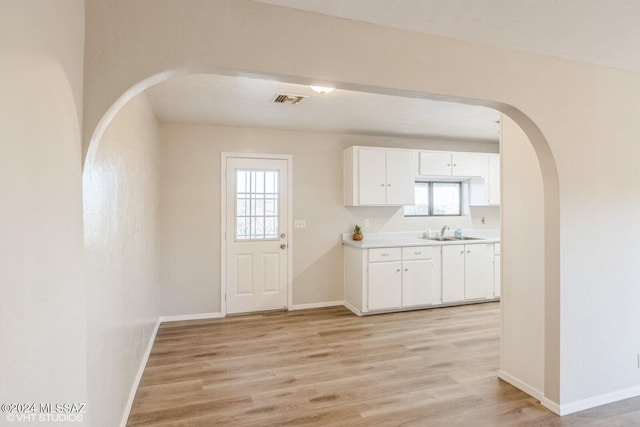 kitchen with white cabinetry, sink, and light wood-type flooring