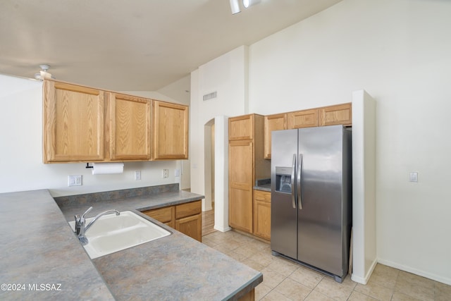 kitchen with light tile patterned flooring, stainless steel fridge, high vaulted ceiling, and sink