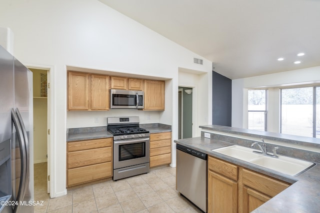 kitchen featuring light tile patterned flooring, appliances with stainless steel finishes, vaulted ceiling, and sink