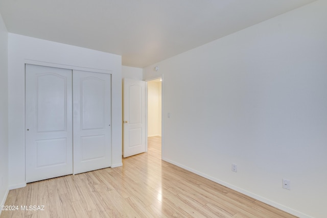 unfurnished bedroom with light hardwood / wood-style flooring and a closet