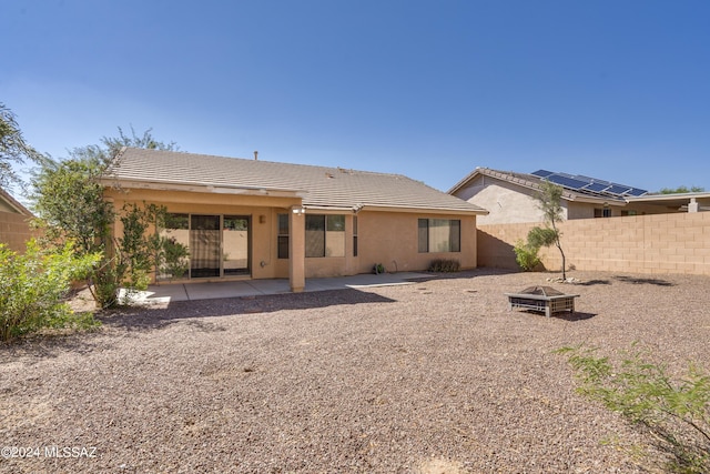 rear view of property featuring a patio and an outdoor fire pit