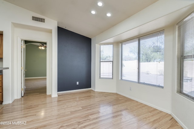 spare room featuring light hardwood / wood-style floors and lofted ceiling