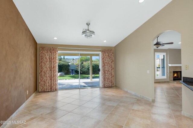 unfurnished living room with lofted ceiling, baseboards, visible vents, and arched walkways