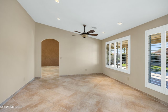 empty room featuring recessed lighting, visible vents, a ceiling fan, arched walkways, and baseboards