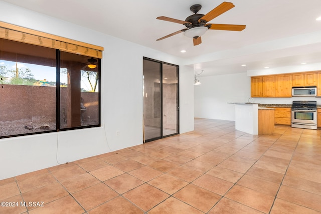 kitchen with light tile patterned flooring, stainless steel appliances, and ceiling fan with notable chandelier