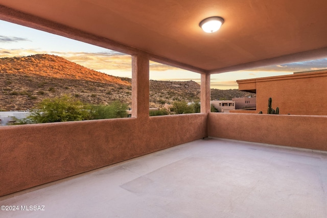 patio terrace at dusk with a mountain view and a balcony