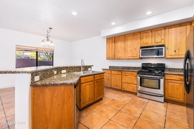 kitchen featuring a kitchen island with sink, an inviting chandelier, sink, decorative light fixtures, and stainless steel appliances