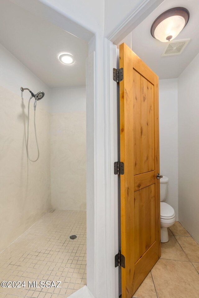 bathroom featuring tile patterned flooring, toilet, and walk in shower