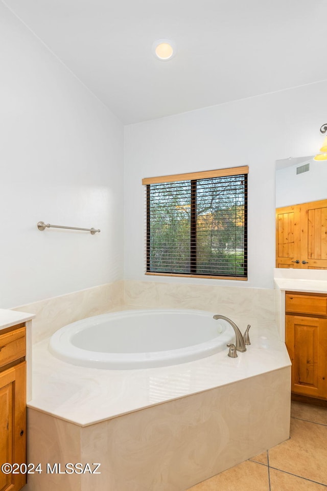 bathroom featuring tile patterned flooring, vanity, and tiled tub