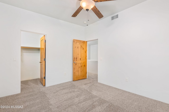 unfurnished bedroom with ceiling fan, a closet, light colored carpet, and a spacious closet