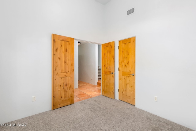 spare room with light colored carpet and a towering ceiling