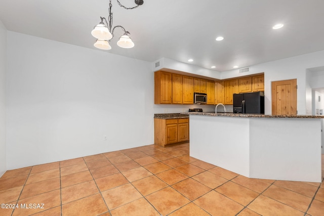 kitchen with stone countertops, black fridge, hanging light fixtures, light tile patterned floors, and a notable chandelier