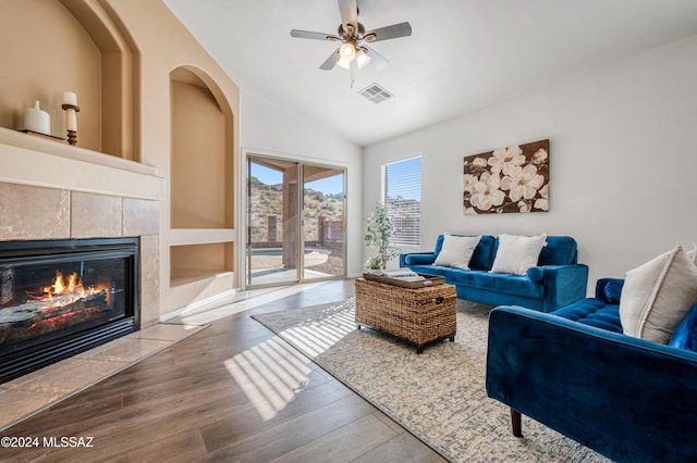 living room with a tile fireplace, ceiling fan, hardwood / wood-style floors, and lofted ceiling