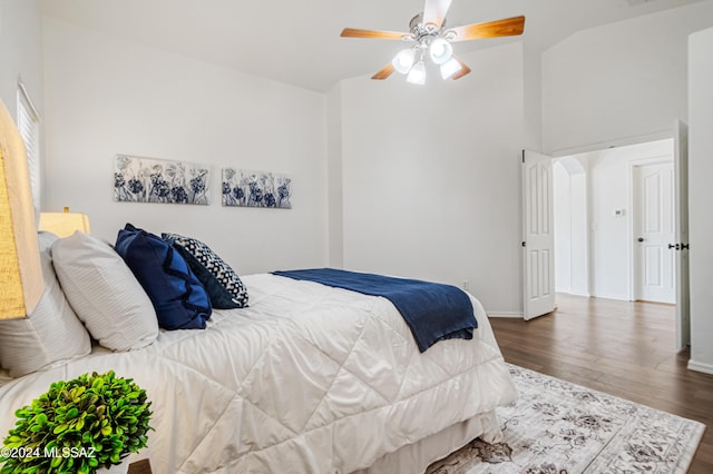 bedroom with ceiling fan, dark wood-type flooring, and lofted ceiling