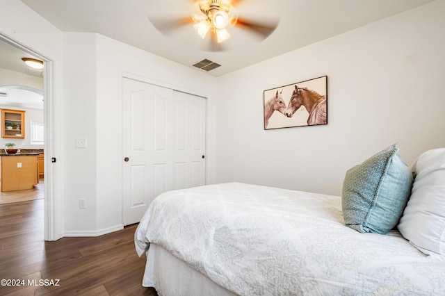 bedroom with a closet, dark wood-type flooring, and ceiling fan