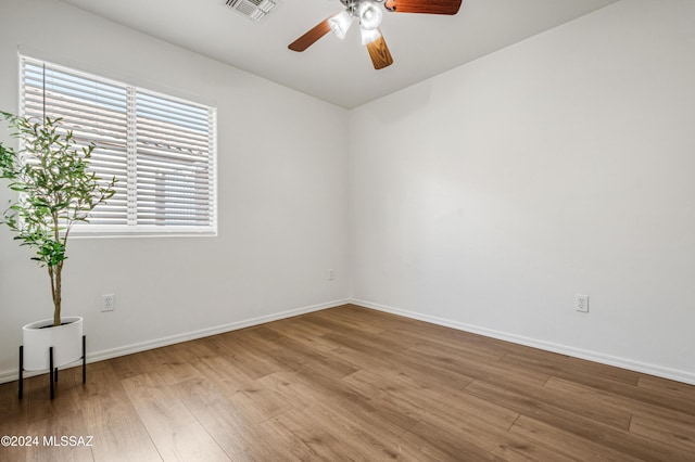 empty room with ceiling fan, plenty of natural light, and hardwood / wood-style flooring