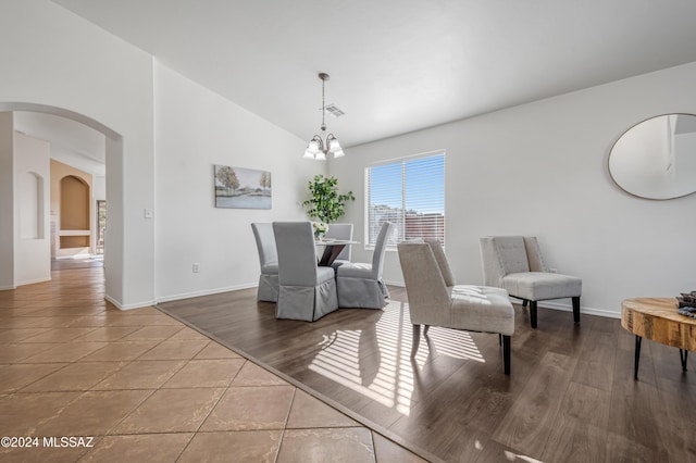 dining space featuring hardwood / wood-style floors, lofted ceiling, and an inviting chandelier