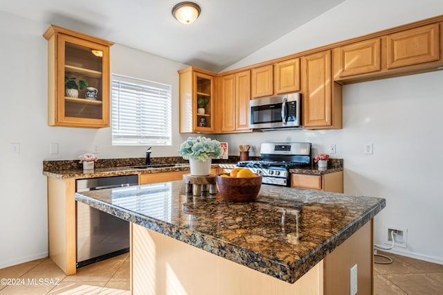 kitchen with lofted ceiling, sink, light tile patterned floors, appliances with stainless steel finishes, and a kitchen island