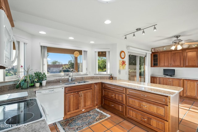 kitchen featuring kitchen peninsula, light stone counters, white appliances, and sink