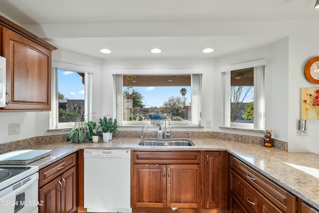 kitchen featuring light stone countertops, white appliances, and sink