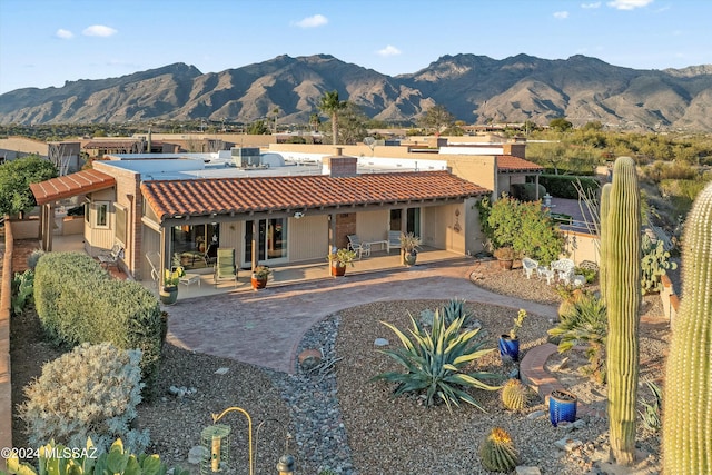 rear view of property with central AC unit, a mountain view, and a patio area