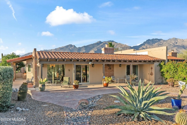 back of property featuring a mountain view and a patio area