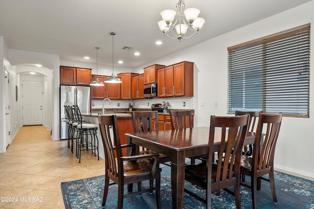 tiled dining space featuring sink and a chandelier