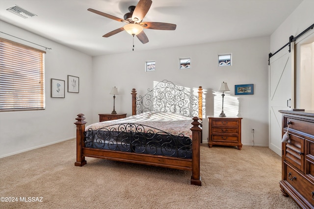 carpeted bedroom with a barn door and ceiling fan