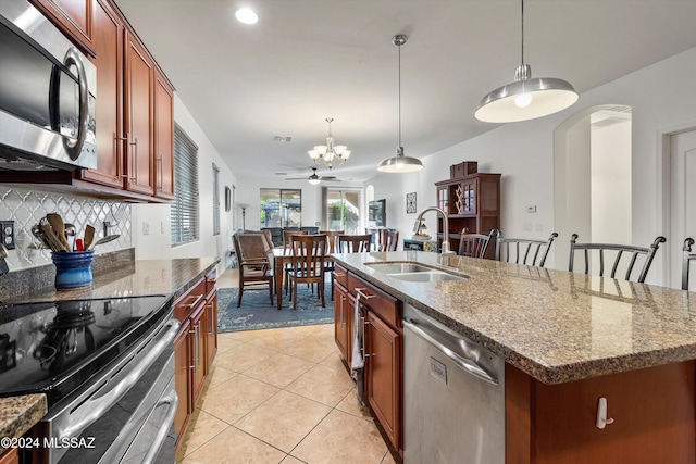 kitchen featuring a center island with sink, decorative light fixtures, sink, and stainless steel appliances