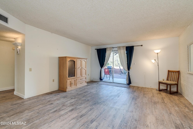 unfurnished living room featuring light hardwood / wood-style floors and a textured ceiling