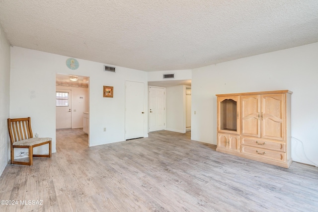 interior space featuring light wood-type flooring and a textured ceiling