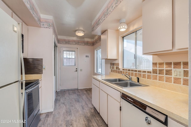 kitchen with white appliances, backsplash, sink, light wood-type flooring, and white cabinetry