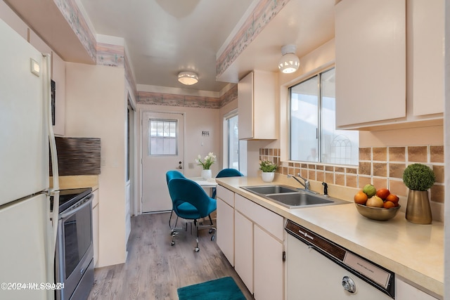 kitchen featuring sink, backsplash, light hardwood / wood-style floors, white appliances, and white cabinets