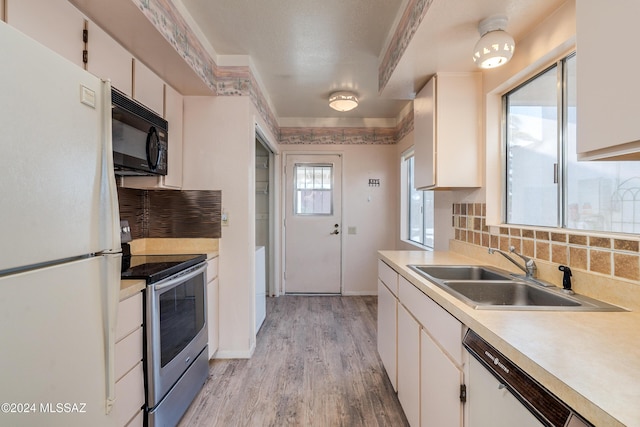 kitchen with electric range, white fridge, white cabinets, and sink