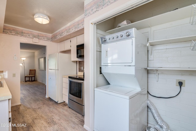 kitchen with white cabinets, stainless steel electric stove, white refrigerator, light hardwood / wood-style flooring, and stacked washing maching and dryer