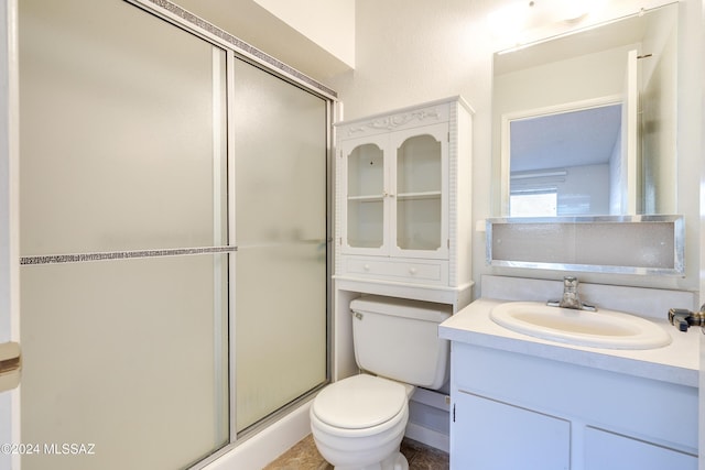 bathroom featuring vanity, toilet, and a shower with shower door