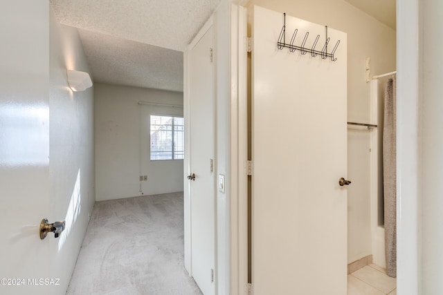 hall with a textured ceiling and light carpet