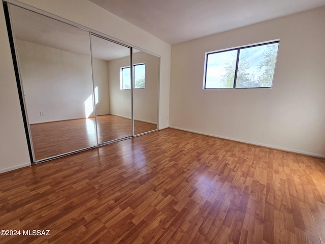 unfurnished bedroom with wood-type flooring and a closet