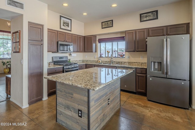 kitchen with appliances with stainless steel finishes, a kitchen island, a wealth of natural light, and sink