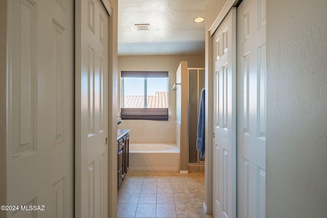 interior space featuring vanity, tile patterned flooring, and plus walk in shower