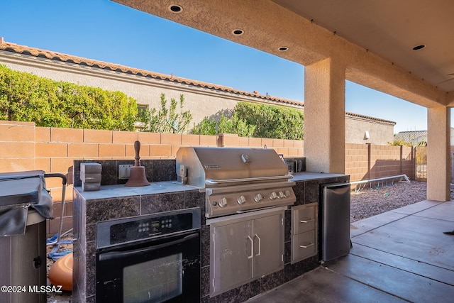 view of patio / terrace featuring an outdoor kitchen and a grill