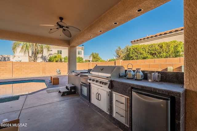 view of patio featuring a swimming pool, area for grilling, ceiling fan, and exterior kitchen