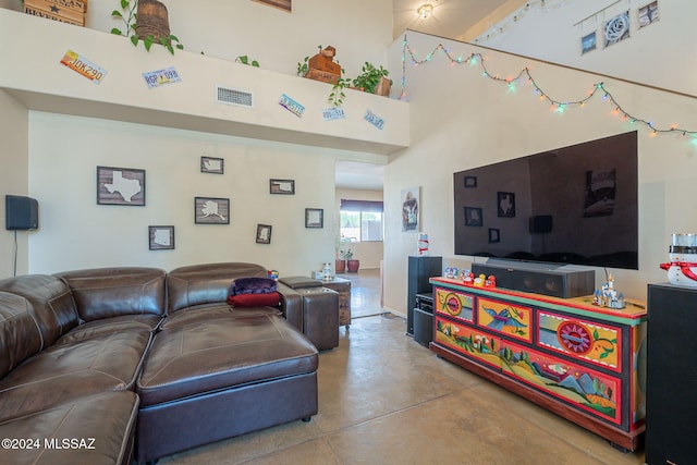 living room with concrete flooring and a high ceiling