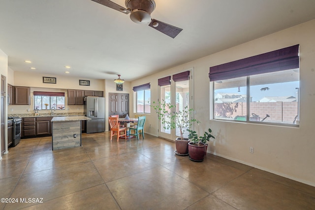 kitchen featuring a wealth of natural light, a kitchen island, light stone countertops, and appliances with stainless steel finishes