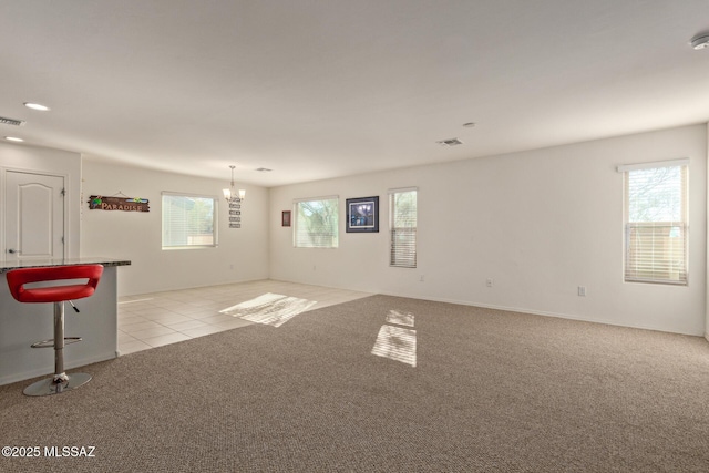 carpeted empty room with a wealth of natural light and a notable chandelier