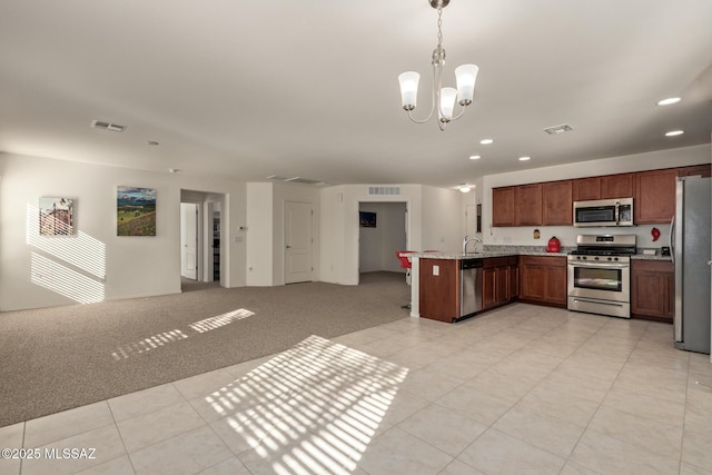 kitchen with appliances with stainless steel finishes, light colored carpet, sink, a notable chandelier, and hanging light fixtures