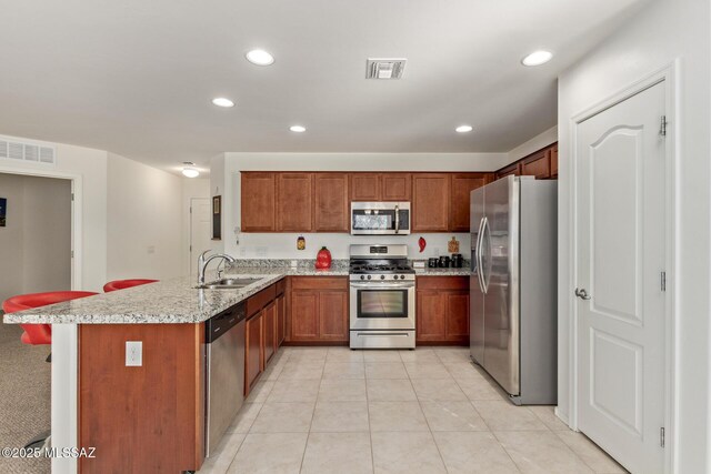 kitchen featuring kitchen peninsula, appliances with stainless steel finishes, light stone countertops, sink, and light tile patterned floors