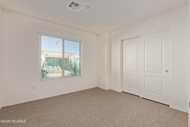 unfurnished bedroom with light colored carpet and a closet