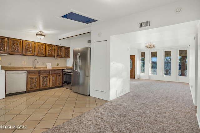 kitchen featuring sink, a notable chandelier, washer / clothes dryer, light tile patterned floors, and appliances with stainless steel finishes